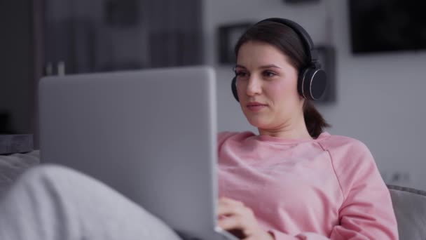 Potret seorang wanita yang bekerja dengan laptop dan mendengarkan musik melalui headphone — Stok Video