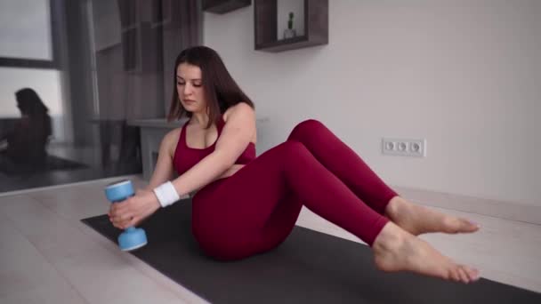 Vrouw doet buikspieroefeningen, buigt borst naar de zijkanten met gewicht — Stockvideo