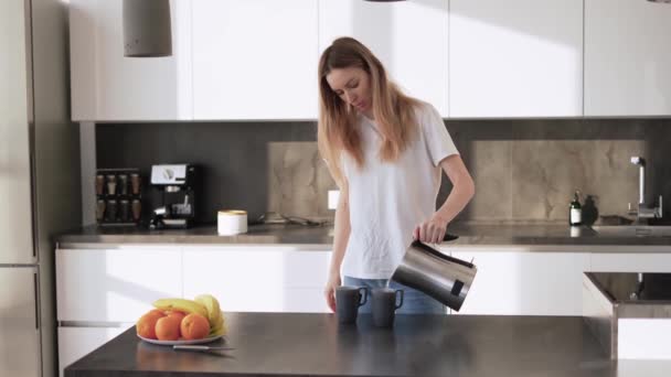 Una joven vierte té en una tazas de una tetera — Vídeo de stock