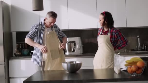 Romantisch paar thuis in de keuken zetten schorten — Stockvideo