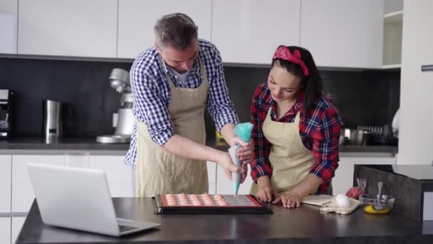 Man piping uit macaron mengsel op een slipmat met wifes ondersteuning — Stockvideo