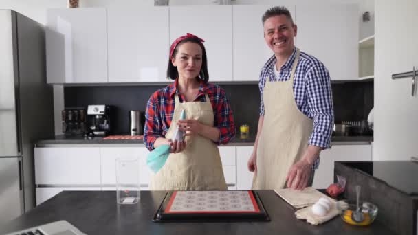 Mutfaktaki pozitif çift evde kurabiye pişiriyor, kamerada konuşuyorlar. — Stok video