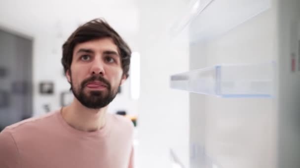 Man opens door of an empty fridge surprised, view from inside — Stock Video