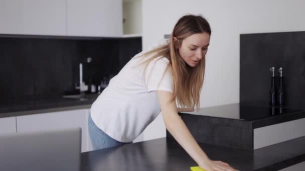 Chica rubia barrer las superficies de la cocina en el mostrador de cocina con un paño — Vídeo de stock