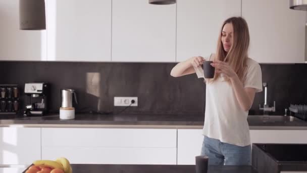 Una joven está bailando en la cocina y tomando café. — Vídeos de Stock