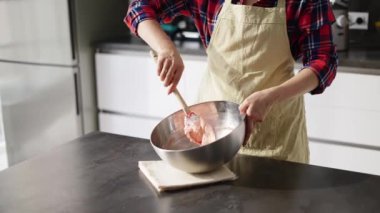 Kadın karıştırma işlemi yapıyor, modern bir mutfakta pasta yapıyor.