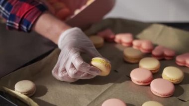 Eldivenli kadın makarnayı tepsiden hediye kutusuna koyar.