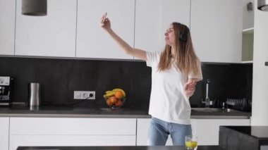 Kulaklıklı kadın mutfakta selfie çekiyor.