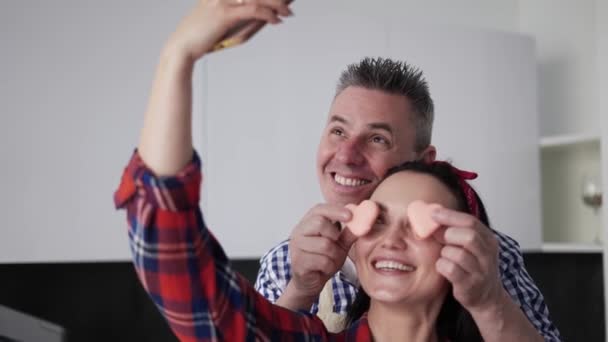 Heureux couple marié prendre un selfie dans la cuisine, se moquer avec des cookies — Video