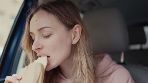 Chica tomando un aperitivo rápido dentro del coche estacionado — Vídeos de Stock