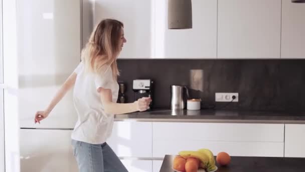 Ξέγνοιαστη κοπέλα στην κουζίνα χορεύει και διασκεδάζει. — Αρχείο Βίντεο