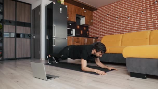 Man doet mixed plank oefening thuis live masterclass via laptop — Stockvideo