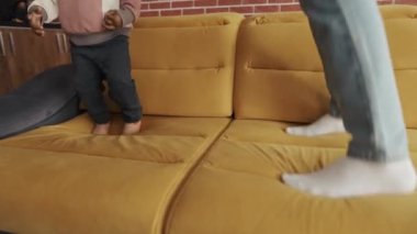 Kırpılmış beden, çoklu etnik baba ve çocuk kanepeye atlıyor.