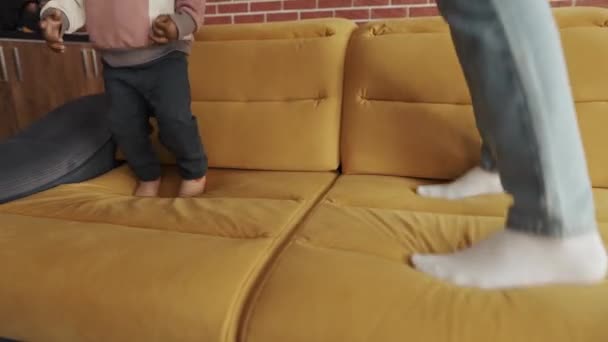 Καλλιεργημένο σώμα πολυεθνικός πατέρας και παιδί γιος άλμα στον καναπέ — Αρχείο Βίντεο