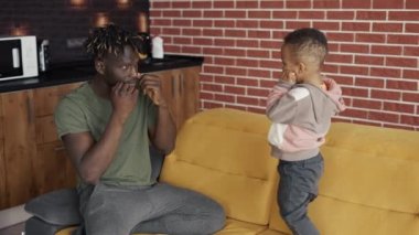 Afrikalı erkek ve küçük oğlu birlikte vakit geçiriyorlar, boks tekmeleriyle oynuyorlar.