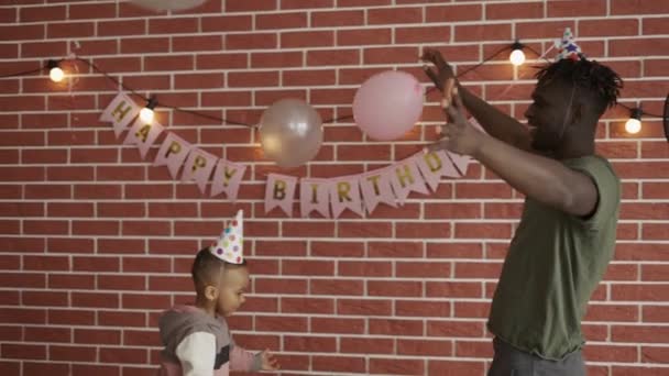 Apa és fia ballonoznak otthon a szülinapi bulin. — Stock videók