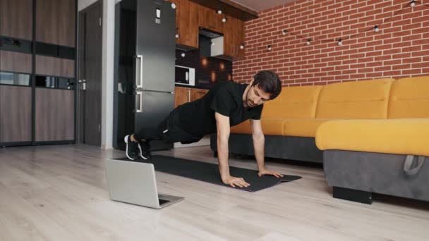 Muž atletický trenér dělá push up doma živé výuky přes notebook nebo video hovor — Stock video