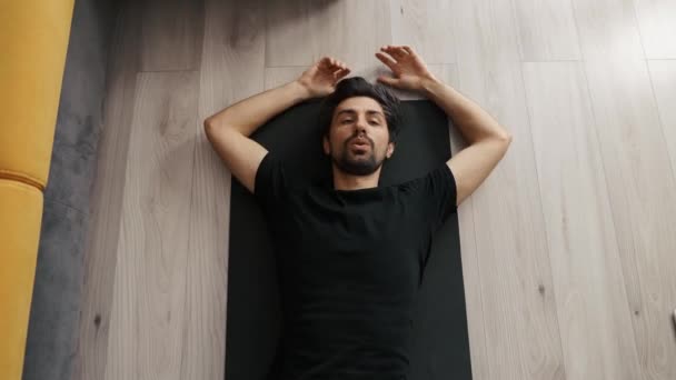 Cansado exausto homem com os braços largos espalhados deitado na aptidão no tapete olhando para cima — Vídeo de Stock