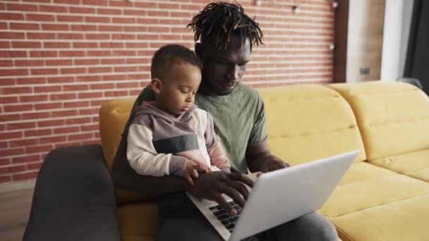 Молодой африканский американский папа учит маленького сфокусированного ребенка сын использовать ноутбук — стоковое видео