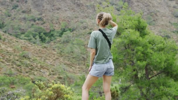 Kobieta stoi sama w górach, ciesząc się widokiem — Wideo stockowe
