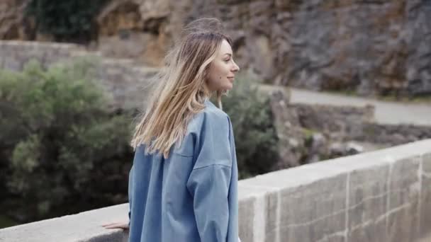 Vrouw toeristische wandelingen door de brug met uitzicht op de rotsen en heuvels — Stockvideo