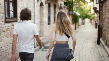 Genç gezgin çift, tarihi bir kasabada dar sokaklarda yürüyor.
