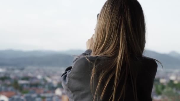 Mulher tirar uma foto, cidade borrada colinas panorama no fundo — Vídeo de Stock