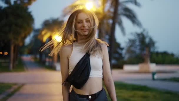 Blonde junge Reisende, die abends durch die Stadt läuft, Zeitlupe — Stockvideo