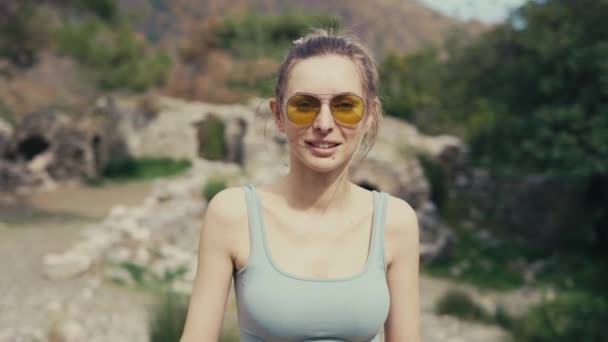 Portrait de belle femme en lunettes de soleil jaunes debout devant la caméra — Video