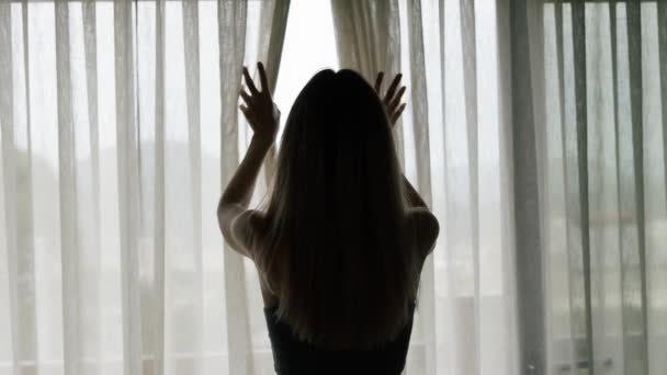 Rear back view of woman opening curtain lace standing at modern hotel looking through window — Stock Video