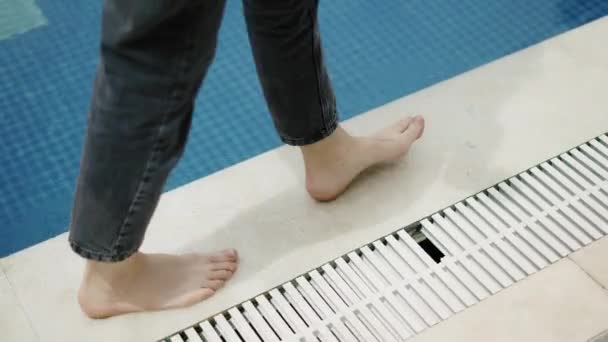 Una ragazza a piedi nudi cammina lungo il bordo di una piscina — Video Stock