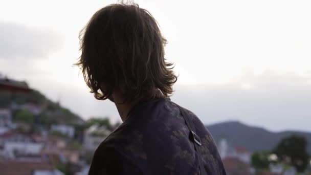 Вид сзади на человека, потрясающий панорамный вид на город, залив моря и горы — стоковое видео