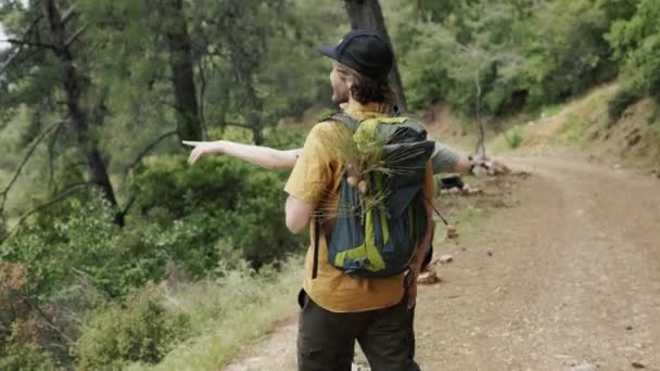 Una feliz pareja de mochileros caminando por el bosque, explorando nuevos lugares — Vídeos de Stock