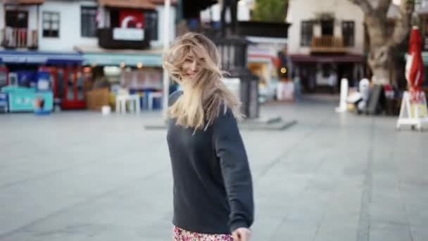 Блондинка танцует на улице, поворачивается, чтобы выразить положительные эмоции — стоковое видео