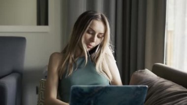 Kanepede dizlerinin üstüne çöküp akıllı telefondan konuşan sarışın kadın.