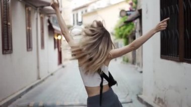 Sarışın kadın dışarıda dans ediyor, etrafında dönüyor, duygusal.