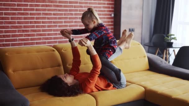 Мать поднимает девушку в воздухе на лодыжки дома — стоковое видео