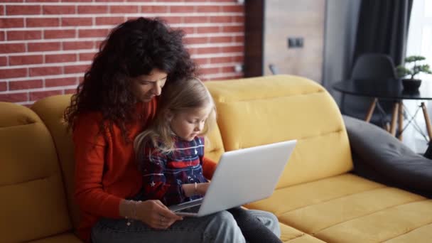 Mutter und Tochter sitzen auf der Couch und benutzen Laptop — Stockvideo