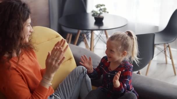 Mamma leker med dottern på soffan sittandes klappa händerna — Stockvideo