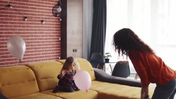 Rizado mamá y su encantadora hija jugando juntos con globos rosados — Vídeos de Stock