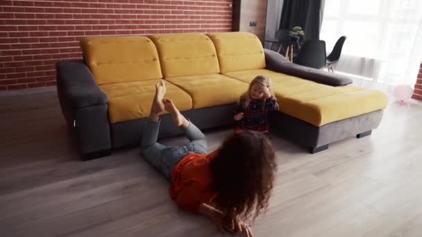 Mała dziewczynka bawi się w domu z matką i wspina się na barana — Wideo stockowe