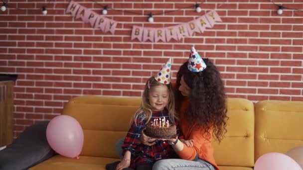 Mãe segurando em mãos bolo de chocolate pequeno aniversário, filha soprando as velas — Vídeo de Stock