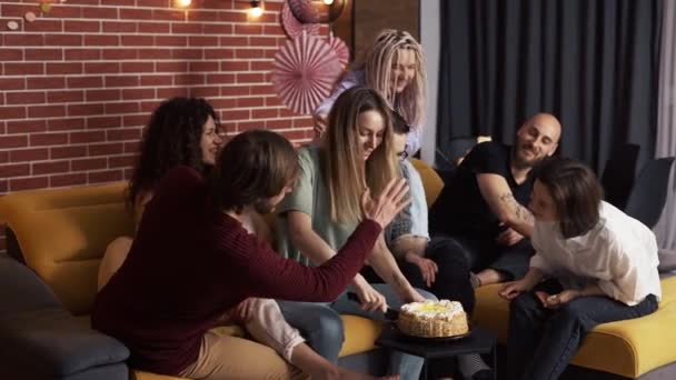Позитивні жінки і чоловіки сидять на дивані збираються з'їсти торт разом — стокове відео
