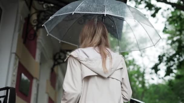 Sarışın kadın yağmurdan saklanmak için yukarı çıkıyor. — Stok video