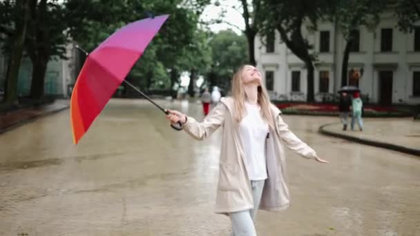 Веселая женщина снимает зонтик, чтобы насладиться дождём в городе — стоковое видео