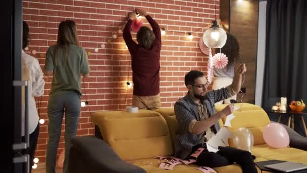 Mannen en vrouwen hebben plezier voorbereiding feest voor vriend, opknoping slingers — Stockvideo