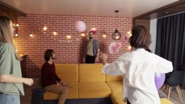 Oturma odasında balonla oynayan bir grup insan, iyi eğlenceler.