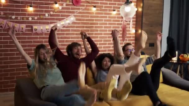 Diversas personas en ropa casual en la sala de estar saltando en el sofá juntos y riendo — Vídeos de Stock
