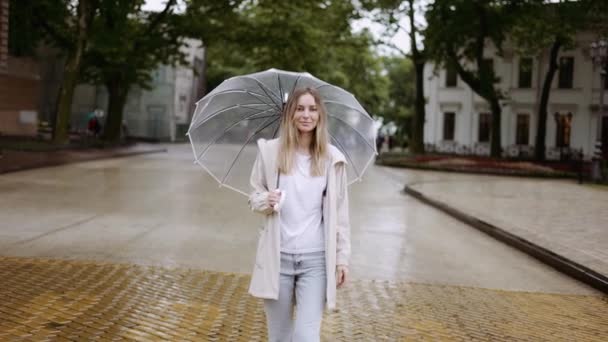 Hermosa mujer caminar con paraguas transparente en día de lluvia — Vídeos de Stock