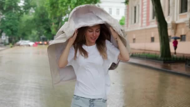 Weibchen unter Regentropfen bedecken Kopf mit Mantel, Zeitlupe — Stockvideo